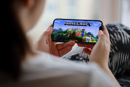Minecraft mobile iOS game on iPhone 15 smartphone screen in female hands during mobile gameplay. Mobile gaming and entertainment on portable deviceのeditorial素材
