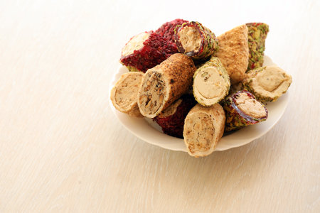 Many rolls of turkish delight with different flavors and fillings in white plate on table. Cuts of...