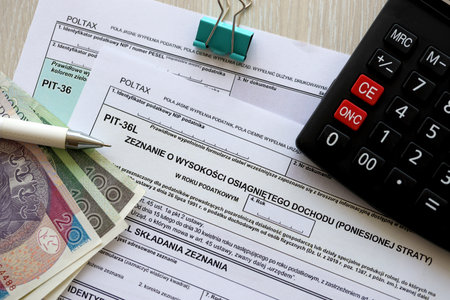 Declaration of the amount of earned income or incurred loss, PIT-36 and PIT-36L tax forms on accountant table with pen and polish zloty money bills close upの写真素材