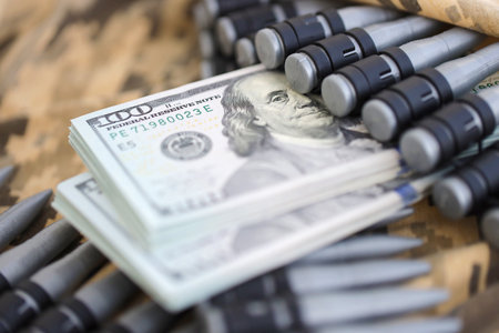 Bundles of dollars and a machine gun belt on the camouflage uniform of a Ukrainian soldier. Concept of war financing, bribe or donation. Help to Ukraine from the USAの写真素材