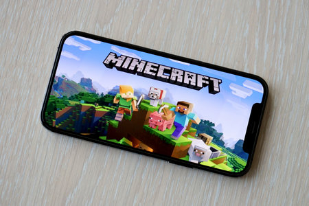 Minecraft mobile iOS game on iPhone 15 smartphone screen on wooden table during mobile gameplay. Mobile gaming and entertainment on portable deviceのeditorial素材
