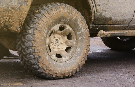 Wheel closeup in a countryside landscape with a mud road. Off-road 4x4 suv automobile with ditry body after drive in muddy road areaの写真素材