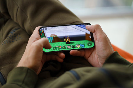 Roblox mobile iOS game on iPhone 15 smartphone screen in male hands during mobile gameplay. Mobile gaming and entertainment on portable deviceのeditorial素材