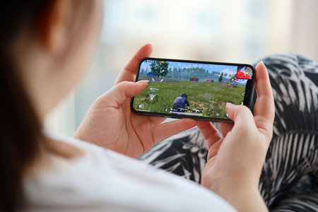 PUBG PlayerUnknowns Battlegrounds mobile iOS game on iPhone 15 smartphone screen in female hands during mobile gameplay. Mobile gaming and entertainment on portable deviceのeditorial素材