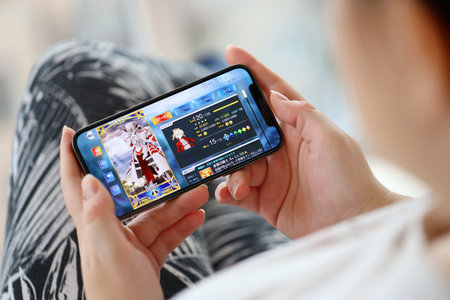 Fate Grand Order mobile iOS game on iPhone 15 smartphone screen in female hands during mobile...