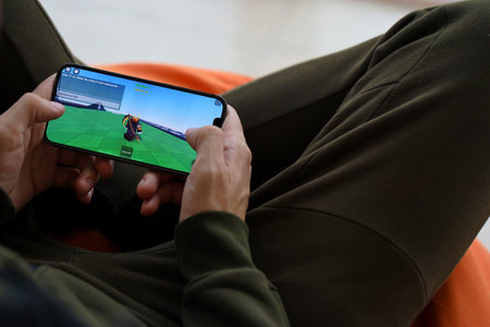 Roblox mobile iOS game on iPhone 15 smartphone screen in male hands during mobile gameplay. Mobile gaming and entertainment on portable deviceのeditorial素材