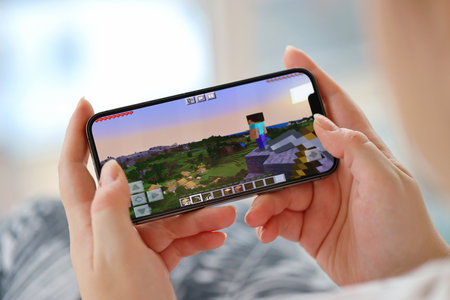 Minecraft mobile iOS game on iPhone 15 smartphone screen in female hands during mobile gameplay. Mobile gaming and entertainment on portable deviceのeditorial素材