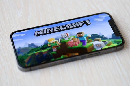 Minecraft mobile iOS game on iPhone 15 smartphone screen on wooden table during mobile gameplay. Mobile gaming and entertainment on portable deviceのeditorial素材