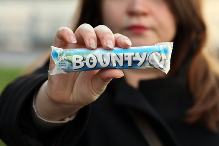 KYIV, UKRAINE - OCTOBER 31, 2023 Bounty chocolate bars with cocoa flavor filling in female hand....
