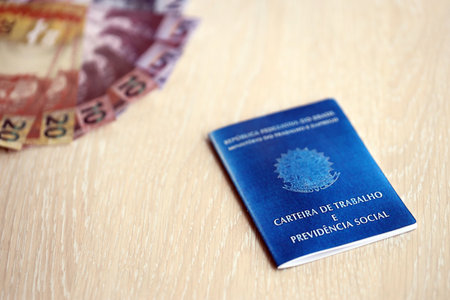 Brazilian work card and social security blue book and reais money bills close up