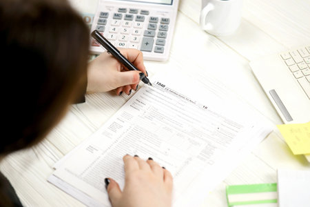 Accountant fill American tax form 1040 Individual income tax return in end of tax period. Taxation and paperwork routine in United Statesの写真素材