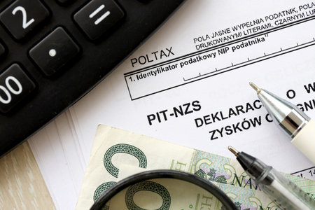 Declaration of income amount from unrealized profits obtained by enterprise as inheritance, PIT-NZS form on accountant table with pen and polish zloty money bills close upの写真素材