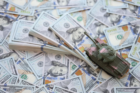 Toy tank on US hundred dollar bills banknotes close up. The concept of war costs, military spending and economic crisisの写真素材
