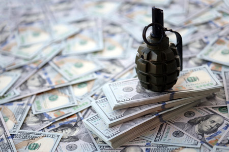 Grenade with a check against the background of huge amount of american dollar bills close upの写真素材