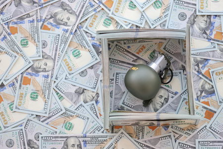 Grenade with a check against the background of huge amount of american dollar bills close upの写真素材