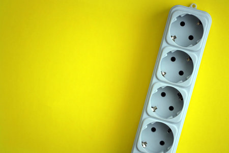 White electrical multi plug extender with european socket on bright yellow background close upの写真素材