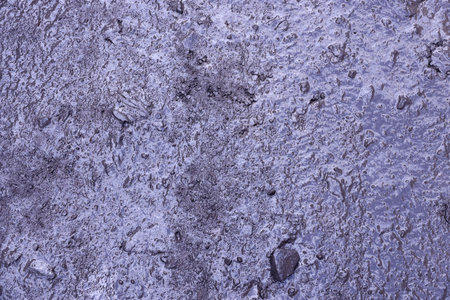 Close up of muddy puddle with small stones on wet surface. Background texture