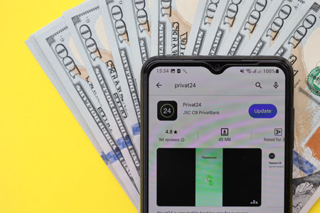 TERNOPIL, UKRAINE - JULY 7, 2023 Privatbank new banking plastic cards with money on table. Privat24 application close upのeditorial素材