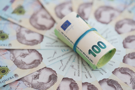 Bunch of hundred euro bills lies on many banknotes of ukrainian hryvnias. Economical default, crisis...