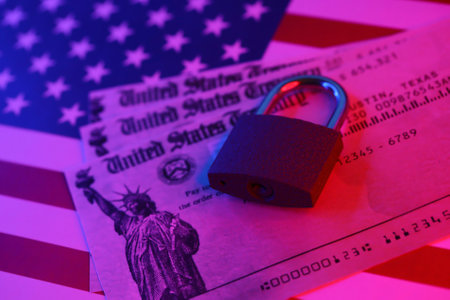United States Treasury refund check or stimulus bill with small padlock on US Flag close up