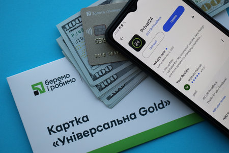 TERNOPIL, UKRAINE - JULY 7, 2023 Privatbank new banking plastic cards with money on table. Privat24 application close upのeditorial素材