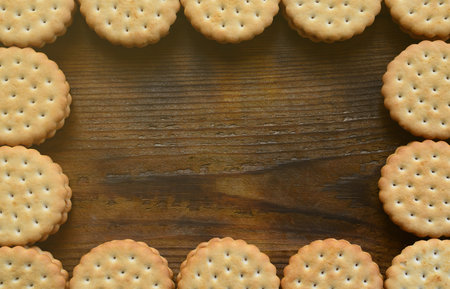 A frame of round cookie sandwich with coconut filling on a dark brown wooden surface. Unusual use of...