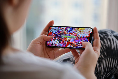 Monster Strike mobile iOS game on iPhone 15 smartphone screen in female hands during mobile...