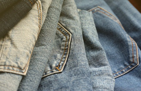 Many jeans in stack in wardrobe room. Row of pants denim jeans in closet. Concept of buy, sell, shopping and fashionable modern clothesの写真素材