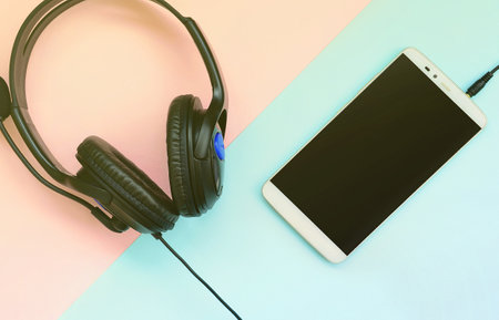 Black headphones and smartphone lies on a colorful pastel violet background. Music listening concept. Portable technology. Flat lay top viewの写真素材