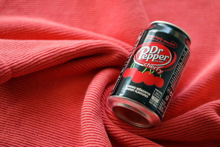 KYIV, UKRAINE - JULY 7, 2023 Dr Pepper cherry drink can on red fabric background