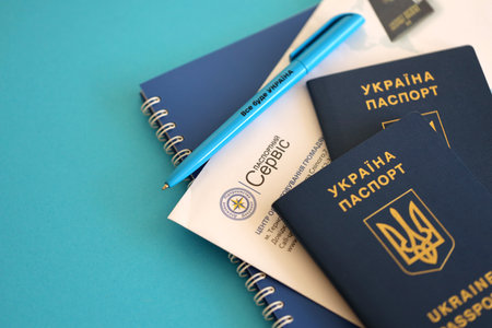 KYIV, UKRAINE - NOVEMBER 27, 2023 Passport service logo with international ukrainian passport and pen on tableのeditorial素材