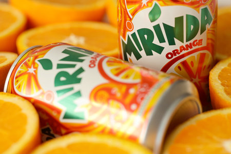 KYIV, UKRAINE - JULY 7, 2023 Mirinda orange drink with many fresh oranges on colorful background