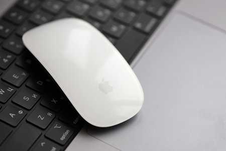 KYIV, UKRAINE - NOVEMBER 27, 2023 Apple Magic Mouse 3rd generation lies with grey MacBook 2021 close upのeditorial素材