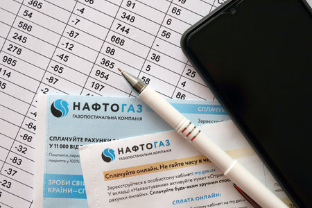 KYIV, UKRAINE - JULY 7, 2023 Naftogaz utility bill document with ukrainian hryvnias money on tableのeditorial素材