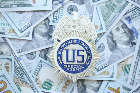 KYIV, UKRAINE - MARCH 9, 2024 US DEA Special Agent badge on many US hundred dollar bills close up
