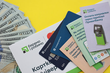 TERNOPIL, UKRAINE - JULY 7, 2023 Privatbank new banking plastic cards with money on table. New card in envelope close upのeditorial素材