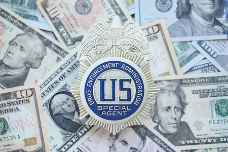 KYIV, UKRAINE - MARCH 9, 2024 US DEA Special Agent badge on many US dollar bills close up