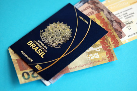 Blue Brazilian passport with money and airline tickets on blue background close up. Tourism and travel conceptの写真素材