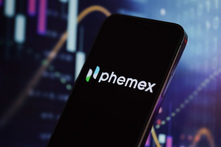 KYIV, UKRAINE - MARCH 15, 2024 Phemex logo on iPhone display screen and crypto currency value charts. Cryptocurrency exchange portalのeditorial素材
