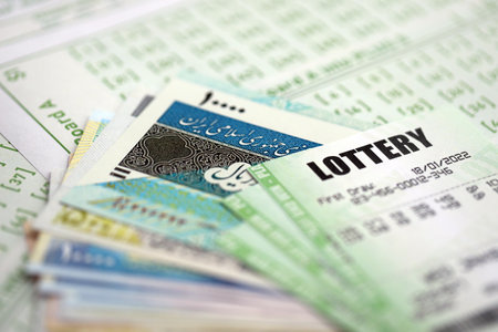 Green lottery tickets and Iranian money bills on blank with numbers for playing lottery close upの写真素材