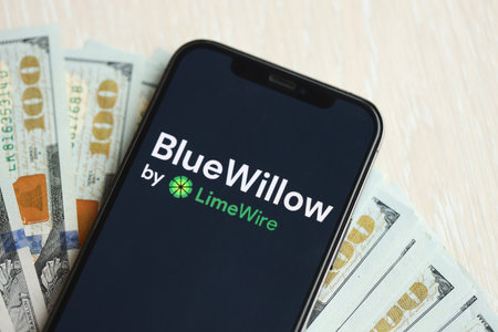 KYIV, UKRAINE - MARCH 17, 2024 BlueWillow logo on iPhone display screen with many hundred dollar...