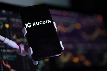 KYIV, UKRAINE - MARCH 15, 2024 Kucoin logo on iPhone display screen and crypto currency value...