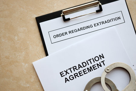 Extradition Agreement and Order Regarding Extradition with handcuffs on table close upの写真素材