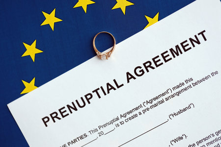 Prenuptial agreement and wedding ring on table. Premarital paperwork process in europe close upの写真素材