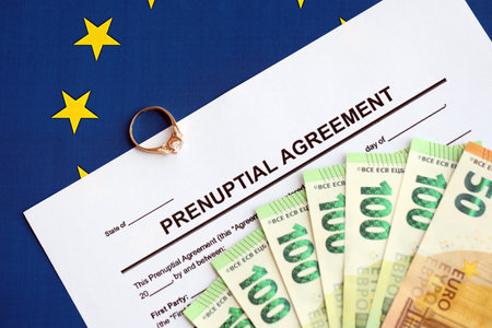 Prenuptial agreement and wedding ring on table. Premarital paperwork process in europe close upの写真素材