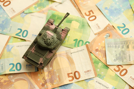 Many euro banknotes and tank. Lot of bills of European union currency and green tank close upの写真素材