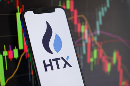 KYIV, UKRAINE - MARCH 15, 2024 HTX logo on iPhone display screen and crypto currency value charts. Cryptocurrency exchange portalのeditorial素材