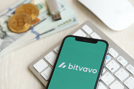 KYIV, UKRAINE - MARCH 15, 2024 Bitvavo logo on iPhone display screen on white keyboard with money and bitcoins. Cryptocurrency exchange portalのeditorial素材