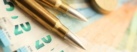 Yellow cartridges and shell casings on euro banknotes. Lot of bills of European union currency and ammo close upの写真素材