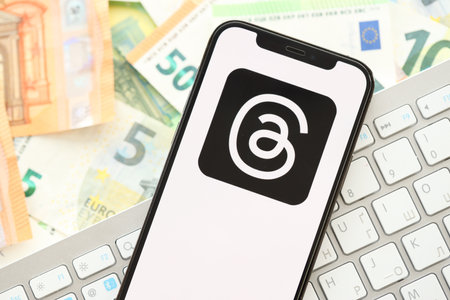 KYIV, UKRAINE - APRIL 1, 2024 Threads icon on smartphone screen on many euro money bills. iPhone display with app logo with european currency euro banknotes and white keyboardのeditorial素材